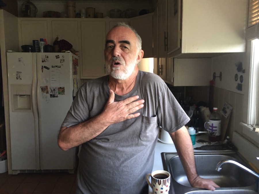 A man at his kitchen sink first thing in the morning, clearing his chest